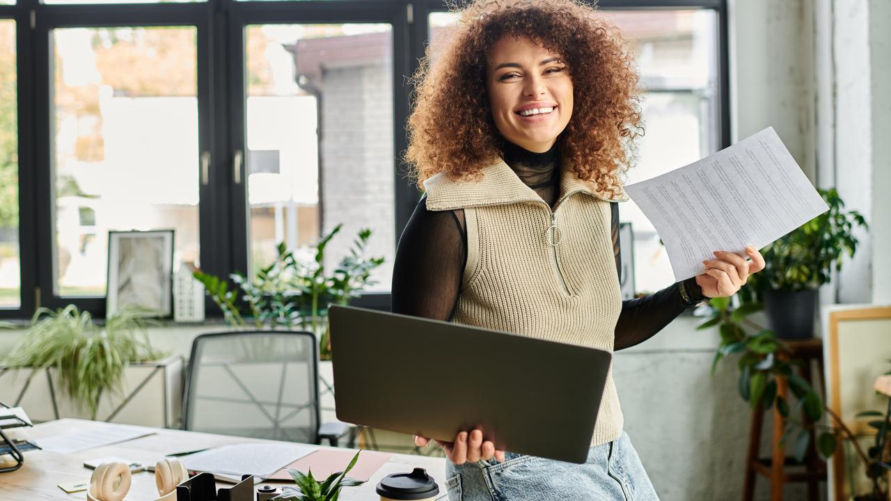 Vrouw met laptop zit op de rand van een bureau